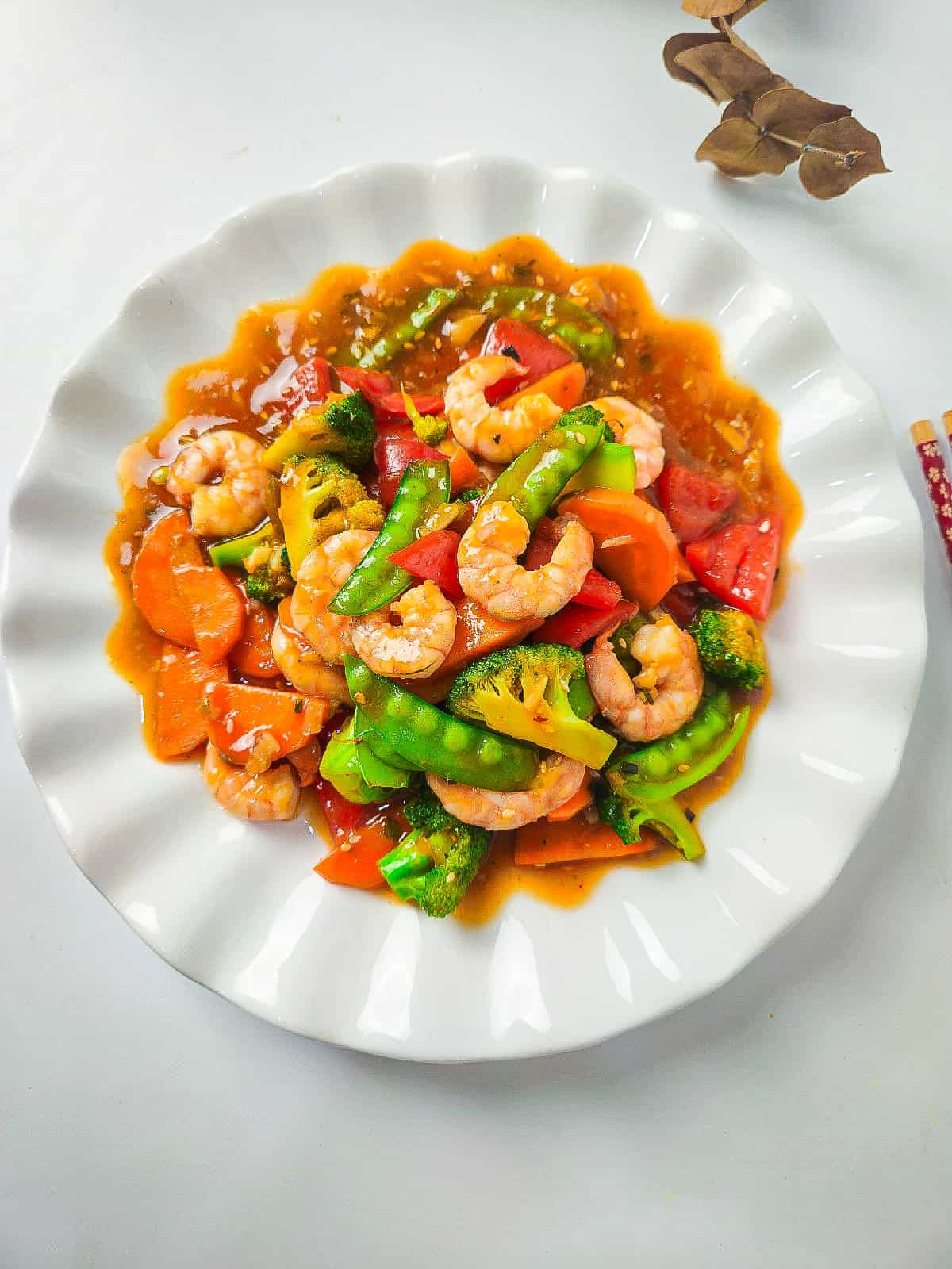 Shrimp and vegetable stir fry served on a white plate with colorful vegetables and savory sauce.