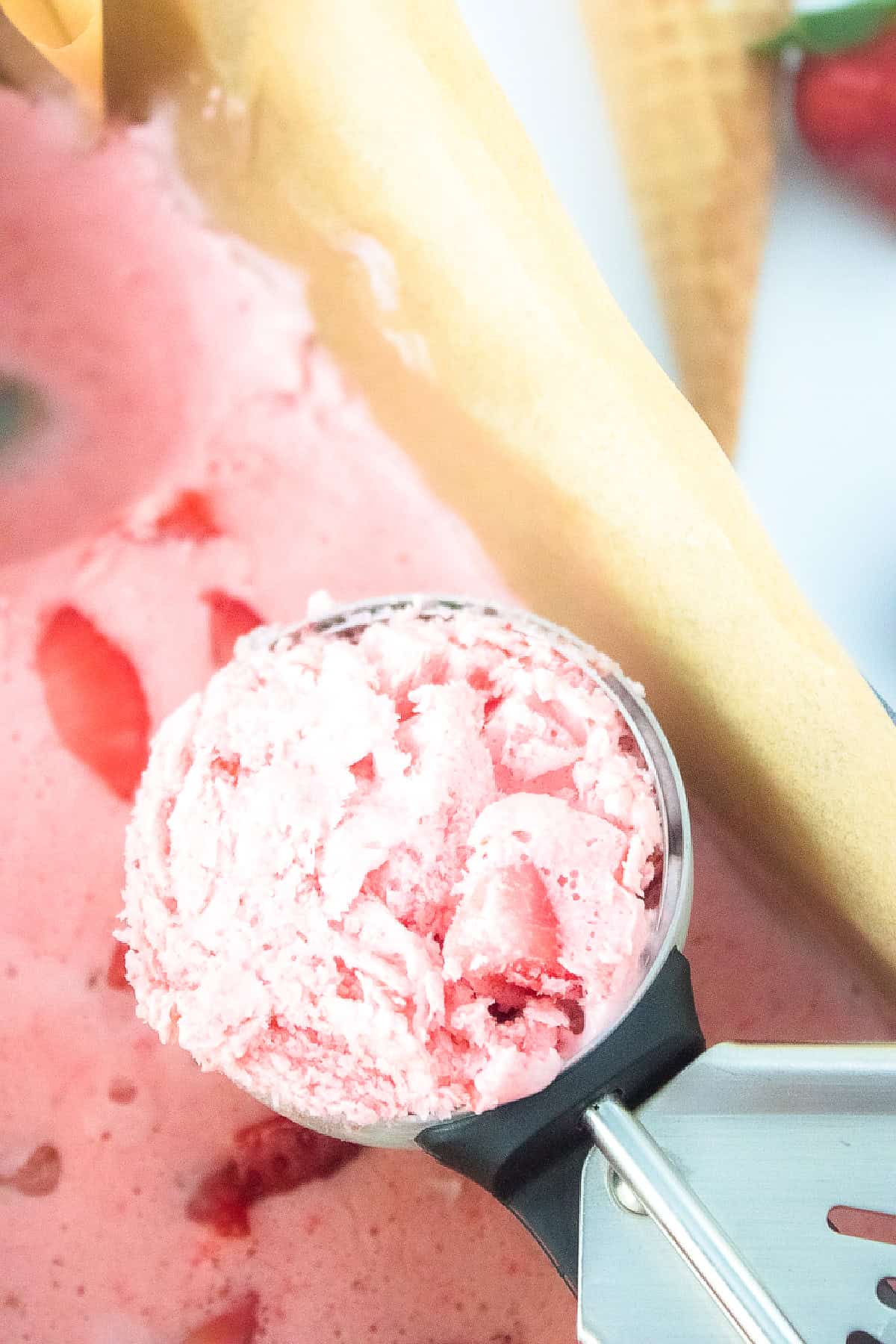 Close-up of a scoop of creamy vegan strawberry ice cream with fresh strawberry chunks.