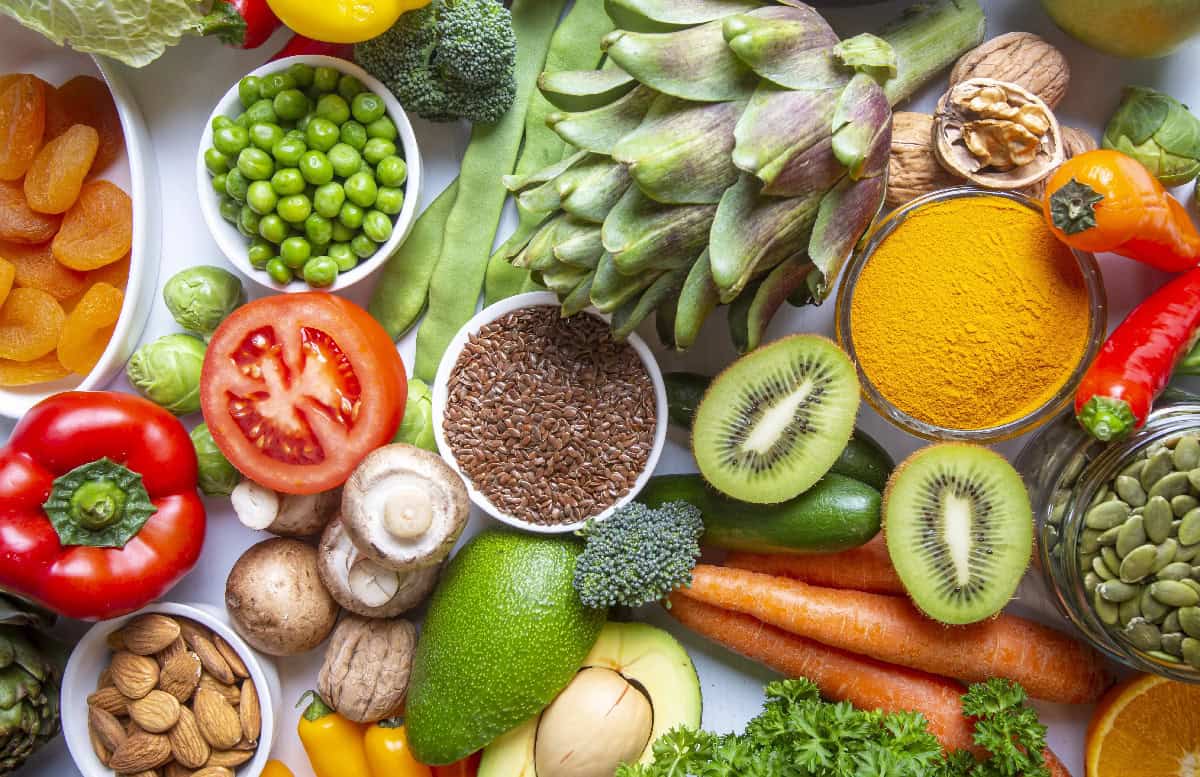 A vibrant collection of fresh fruits, vegetables, nuts, seeds, and spices laid out as examples of nutrient-dense whole foods.
