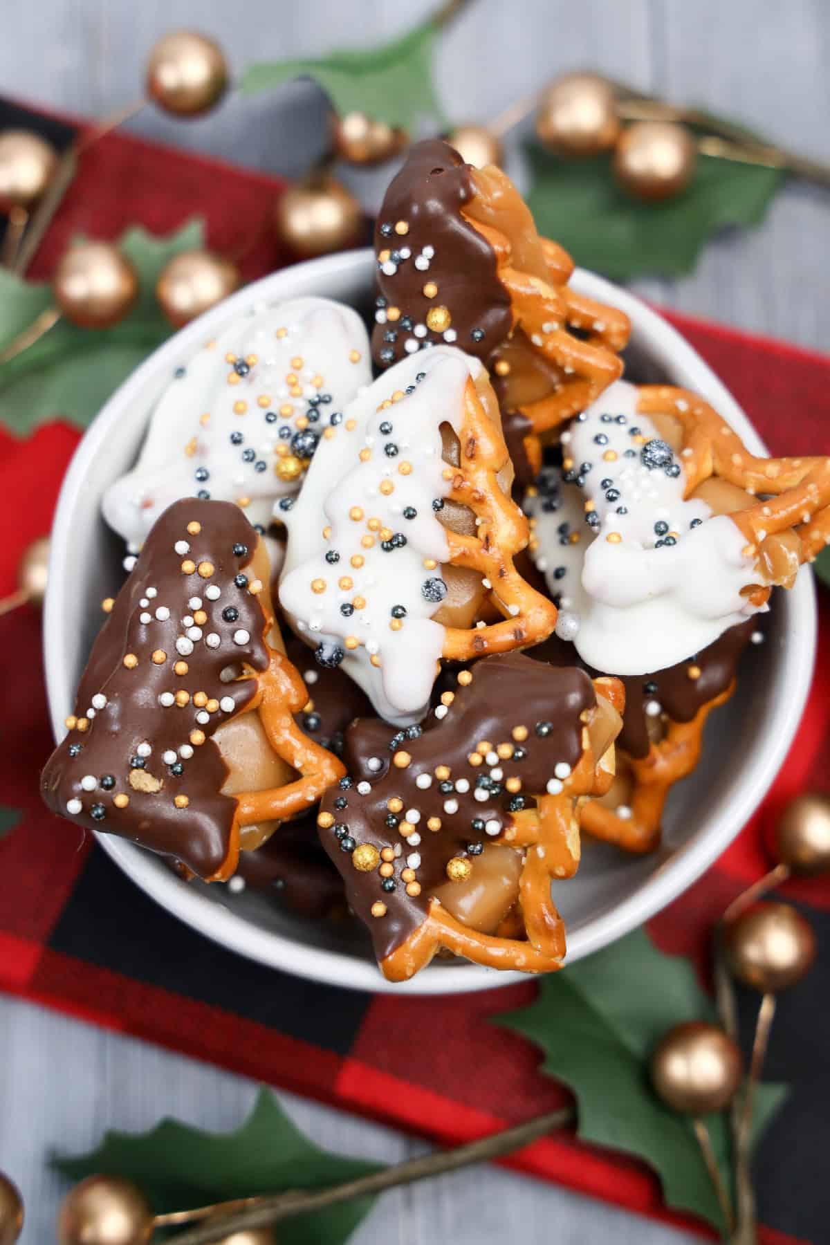 Bowl of chocolate-dipped and white-chocolate-dipped caramel pretzel bites decorated with festive sprinkles.