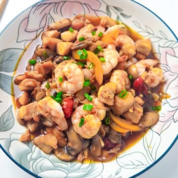 Shrimp and chicken stir fry with mushrooms, bell peppers, and green onions served in a floral bowl.