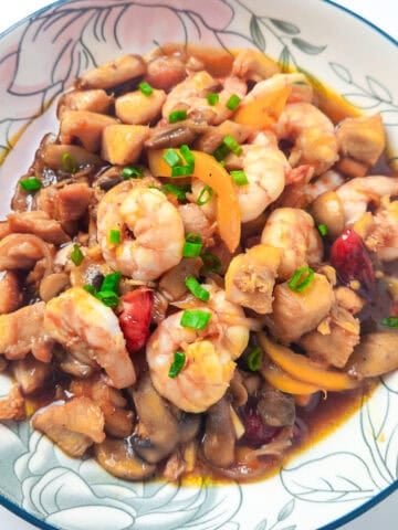 Shrimp and chicken stir fry with mushrooms, bell peppers, and green onions served in a floral bowl.