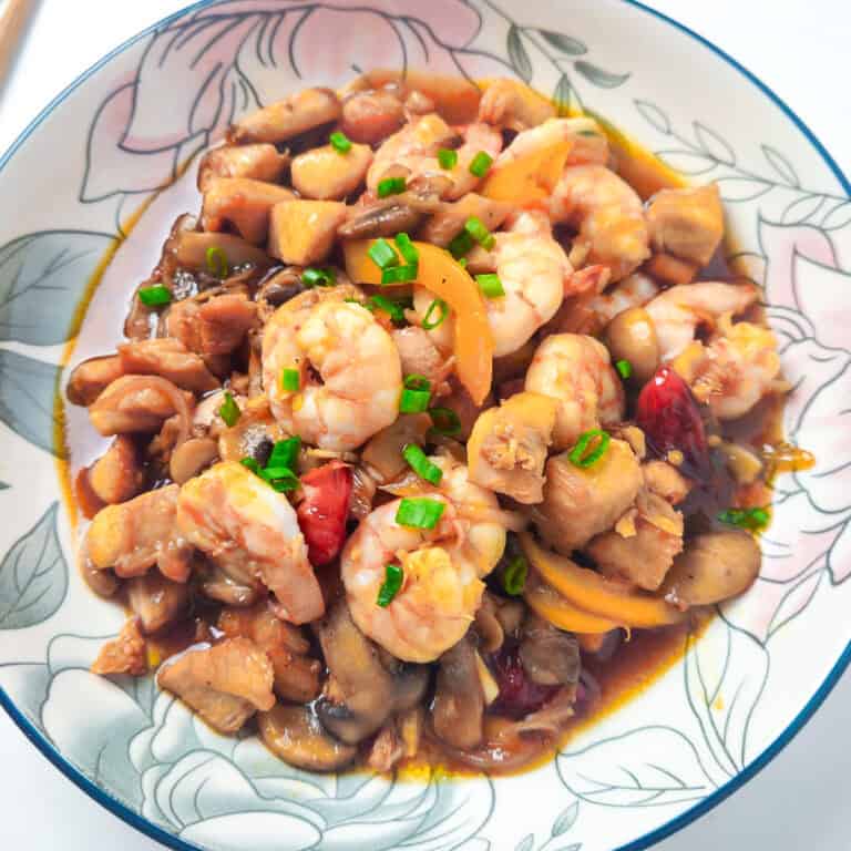 Shrimp and chicken stir fry with mushrooms, bell peppers, and green onions served in a floral bowl.