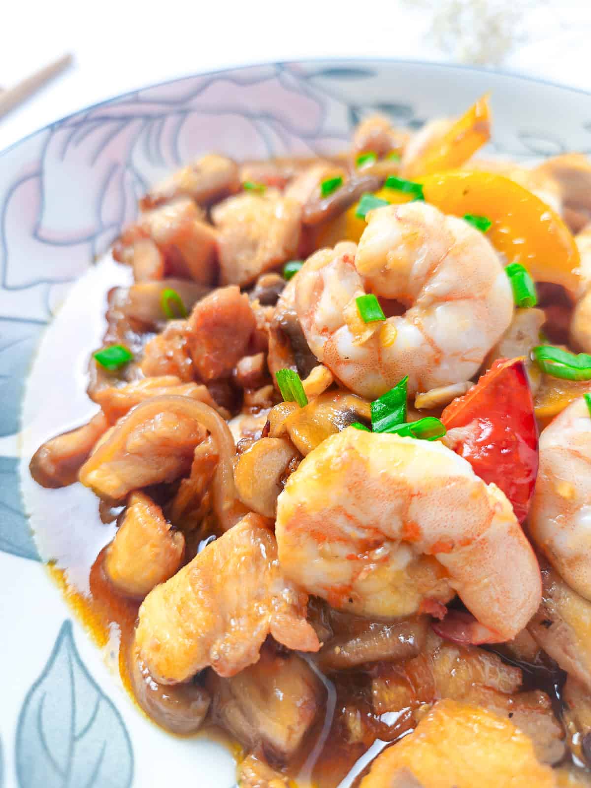 Close-up view of shrimp, chicken, and mushrooms coated in savory stir fry sauce.