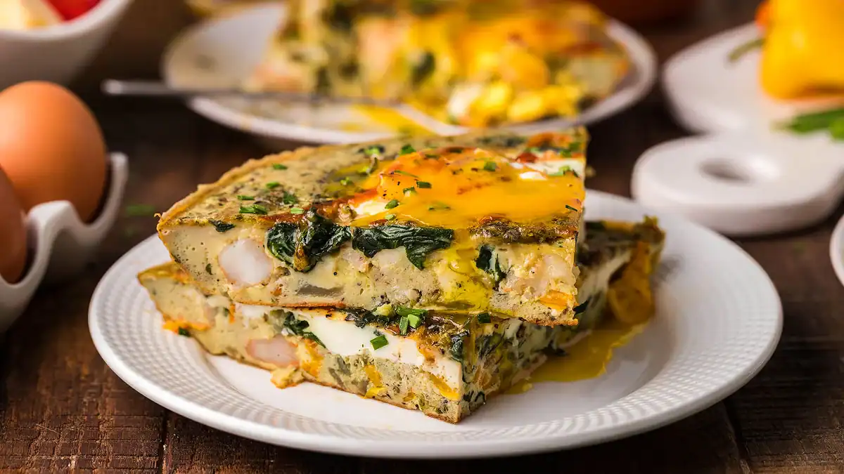 Elegant omelet topped with shrimp, spinach, and sunny-side-up eggs.