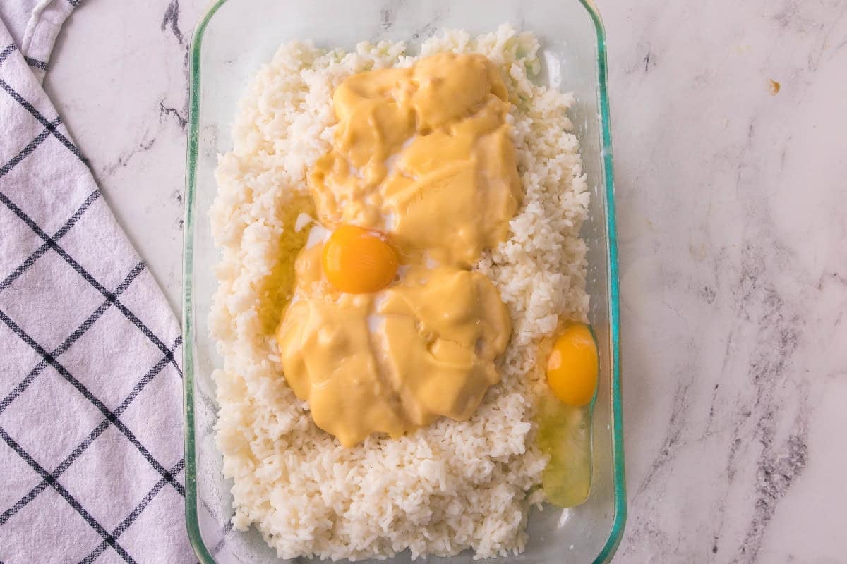 Cream of chicken soup and eggs added on top of cooked rice to make creamy cheesy chicken broccoli rice casserole.