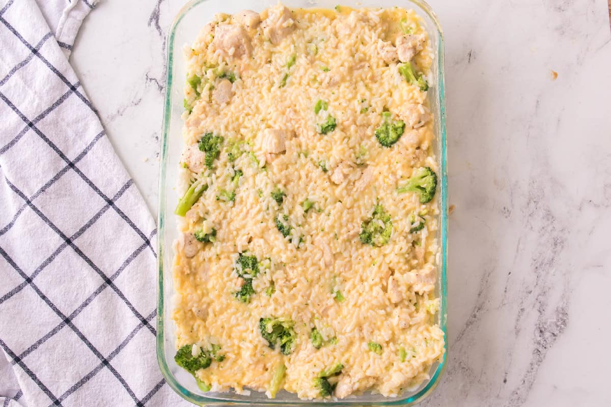 Chicken, broccoli, rice, and cream sauce fully mixed together in a casserole dish ready to bake.