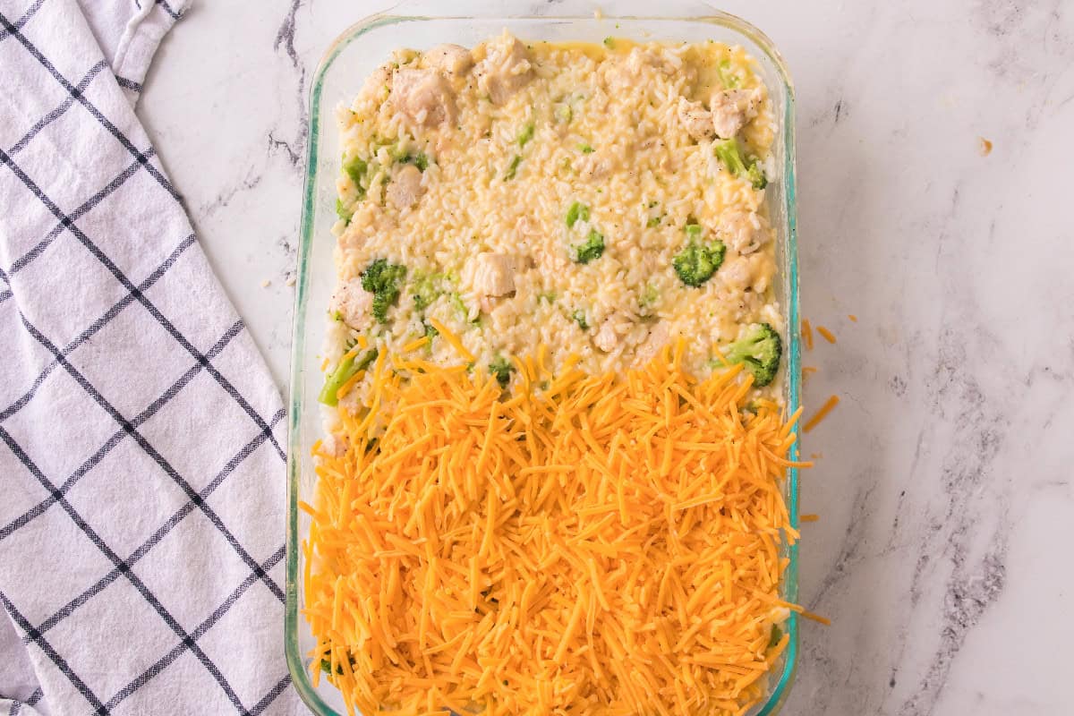 hredded cheddar cheese layered over the top of cheesy chicken broccoli rice casserole before baking.