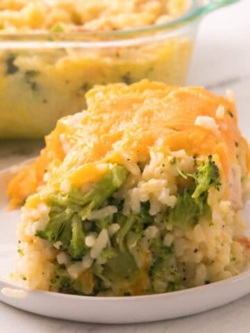A cheesy chicken broccoli rice casserole slice served on a white plate, with tender chicken, broccoli, and melted cheddar in a creamy baked casserole.