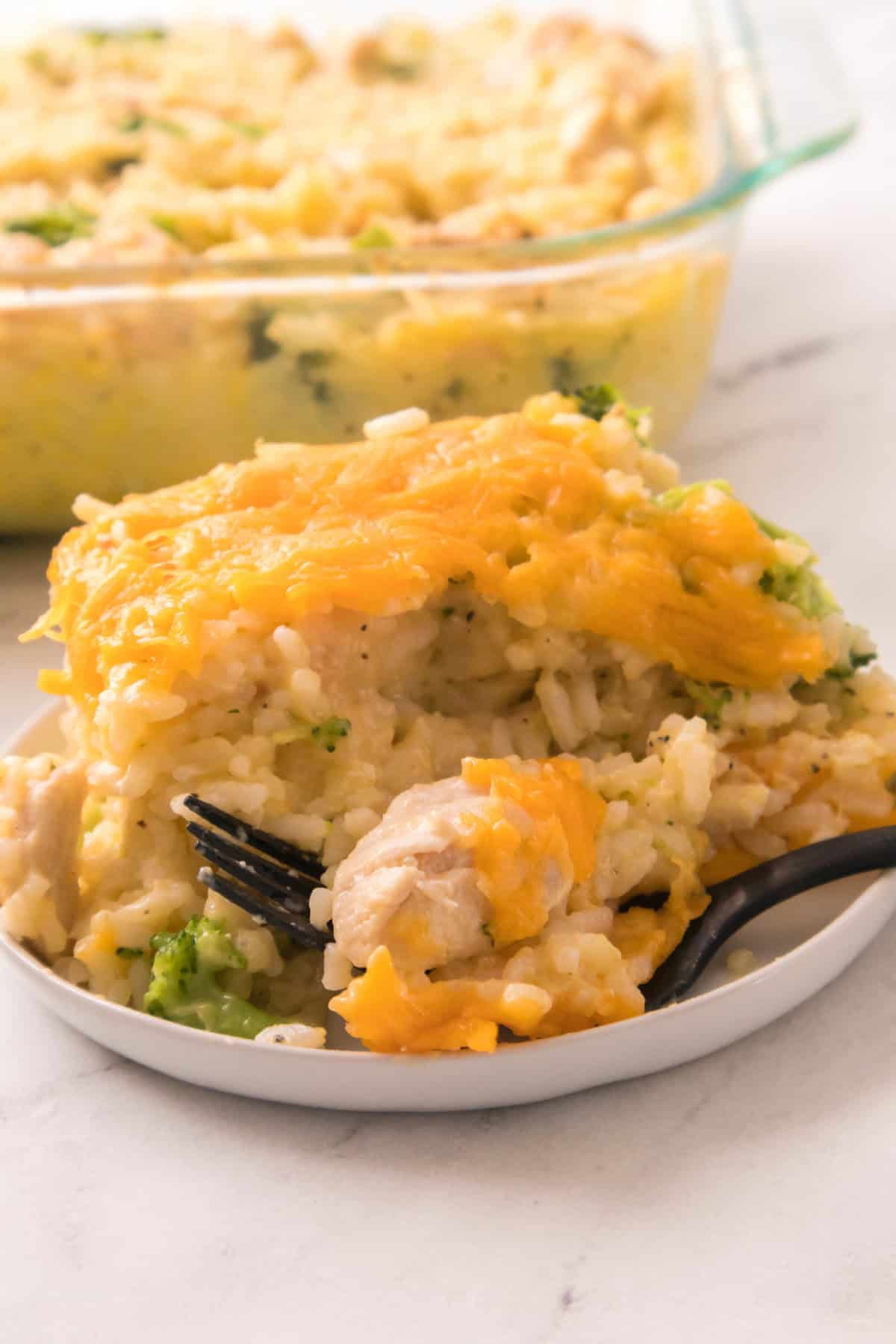Soft and creamy chicken broccoli rice bake served with a fork taking a bite.
