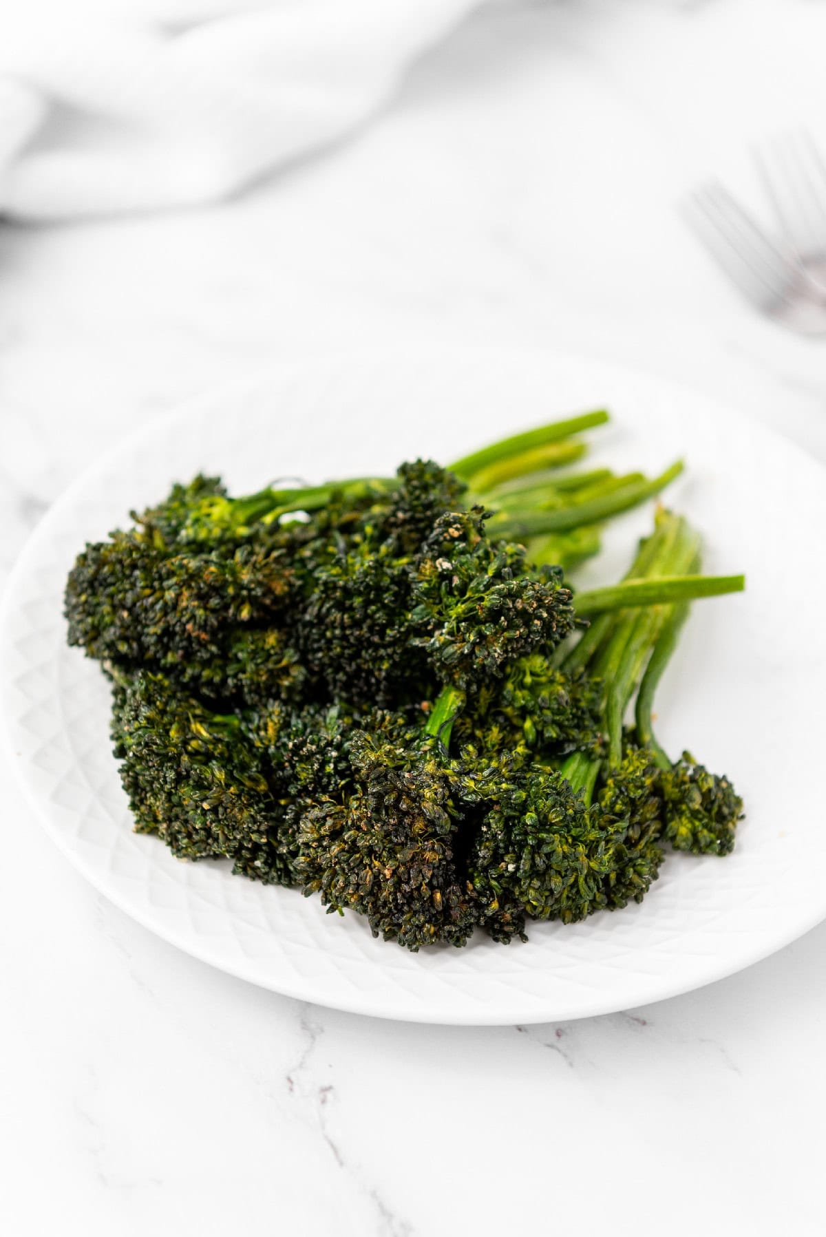 Plate of crispy air fryer broccolini served on a white plate.