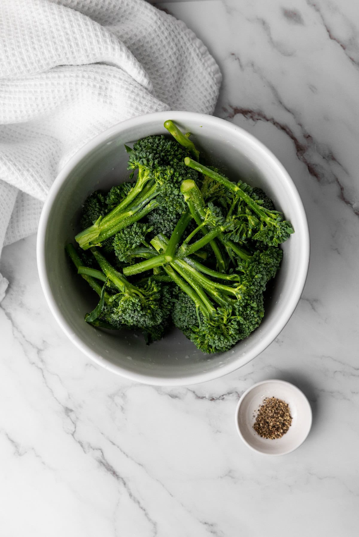 Seasoned broccolini tossed in a bowl with simple olive oil, salt, and pepper.