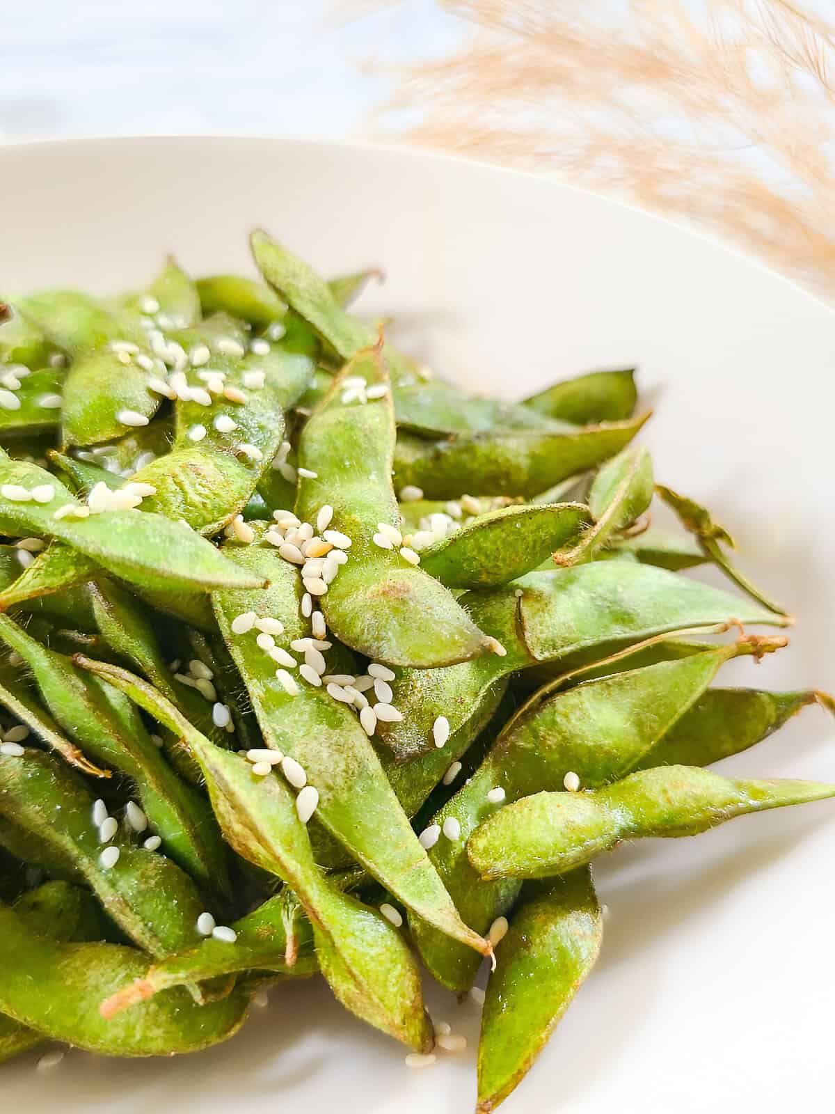 Close-up of air fryer edamame with toasted sesame seeds in a white serving bowl.