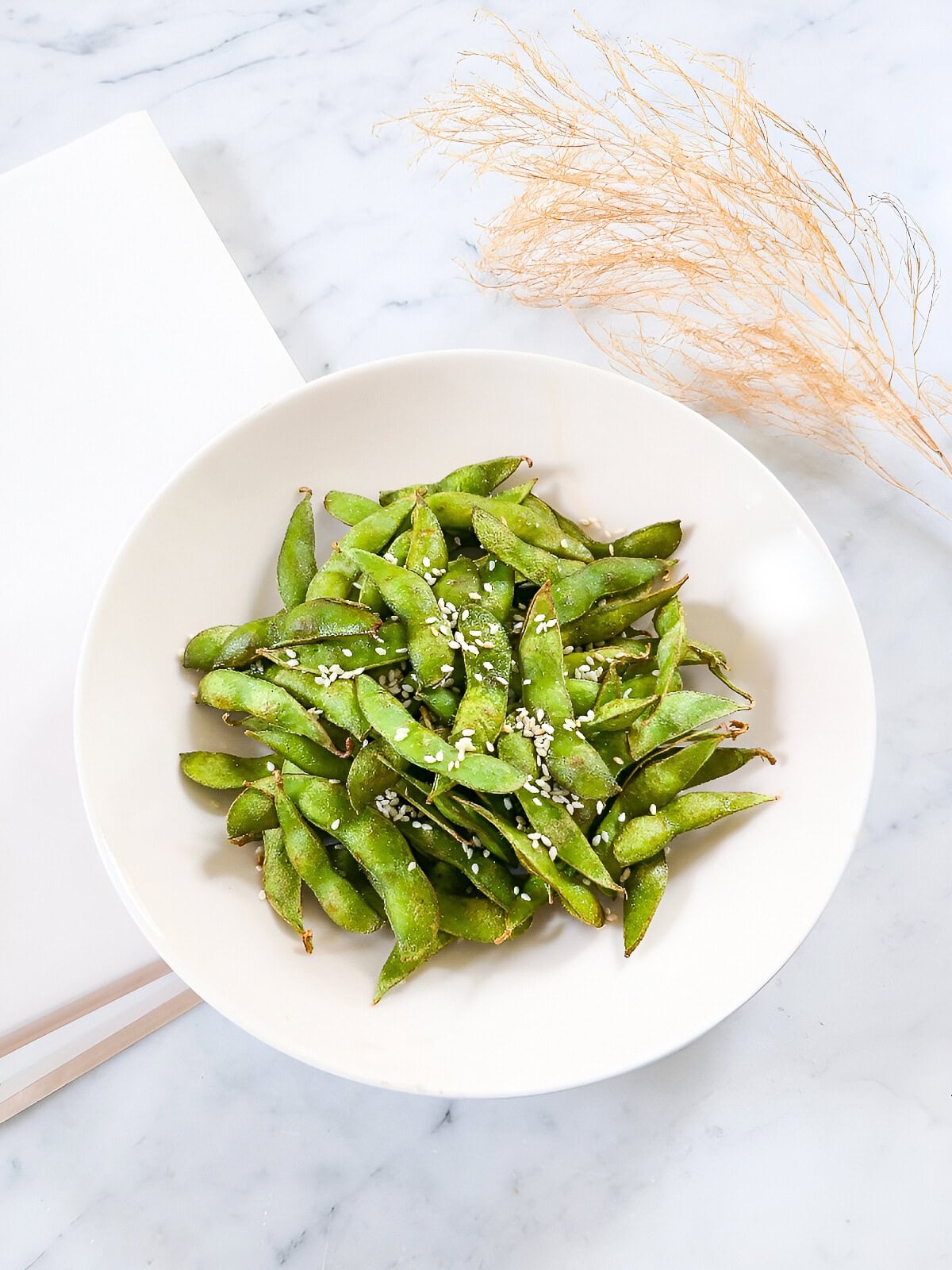 Overhead view of air fryer edamame seasoned with sesame seeds and ready to serve.