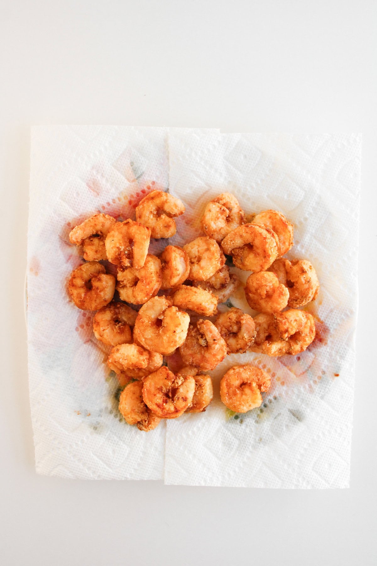 Crispy fried shrimp draining on paper towels.