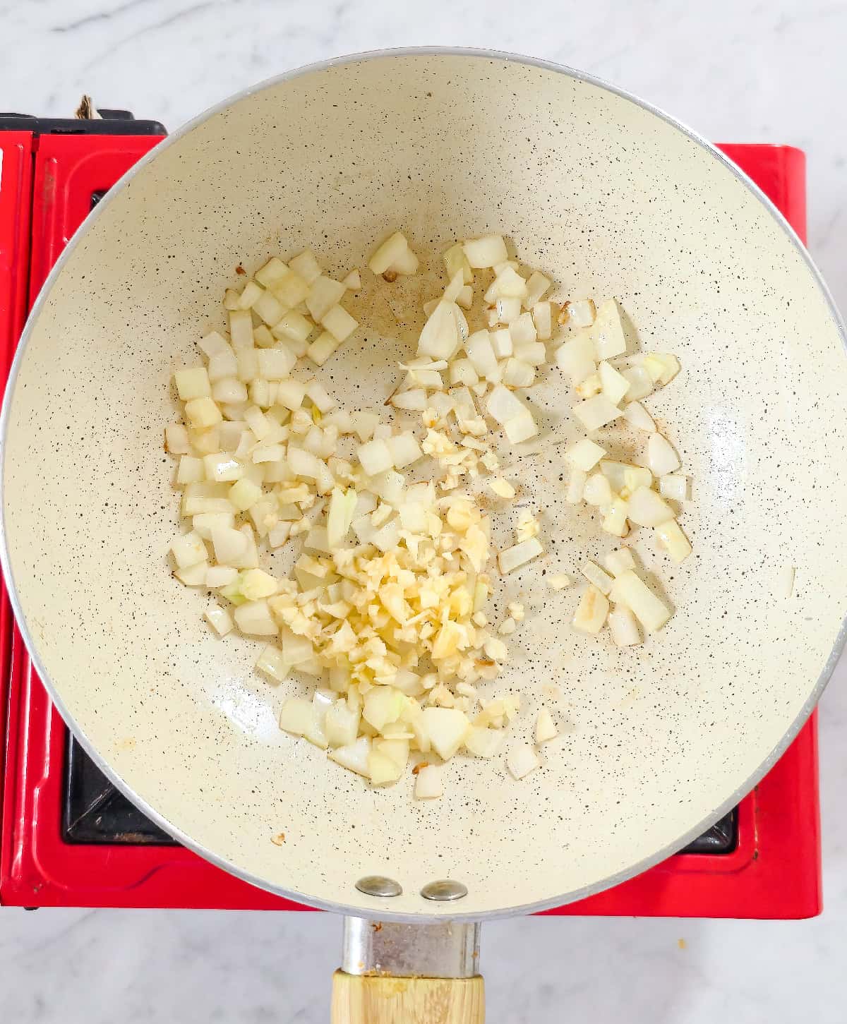 Sautéed onions with freshly minced garlic cooking in a pan.
