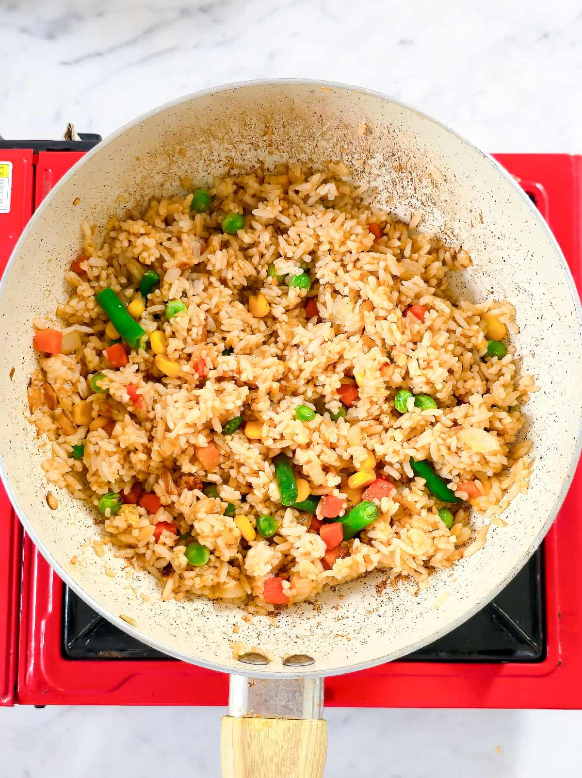 Sauce mixed into rice and vegetables while cooking fried rice.