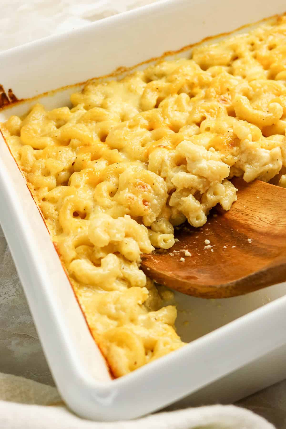 Side view of rich and creamy three-cheese macaroni and cheese in a white baking dish.