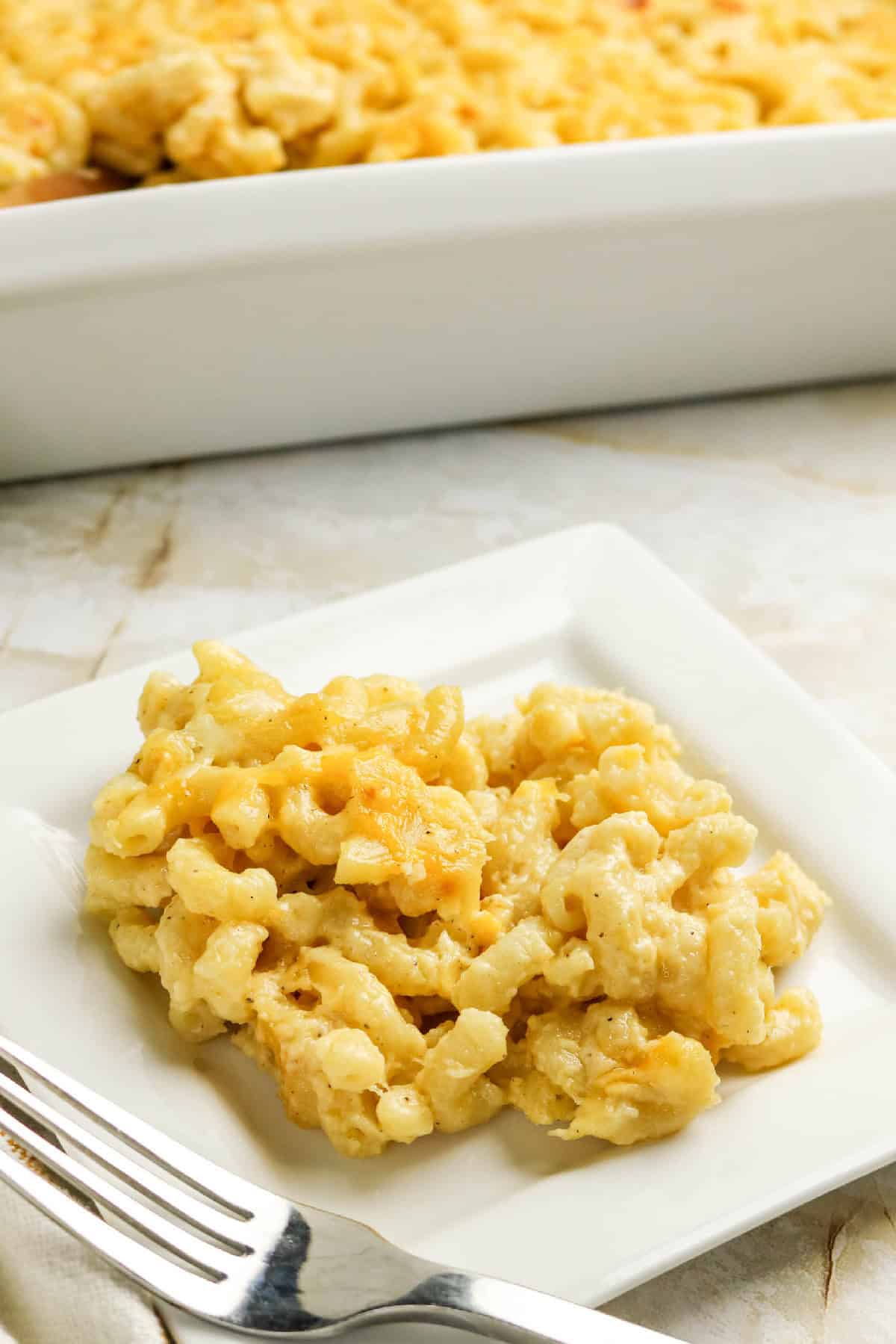 Serving of three-cheese macaroni and cheese on a white plate with a fork.
