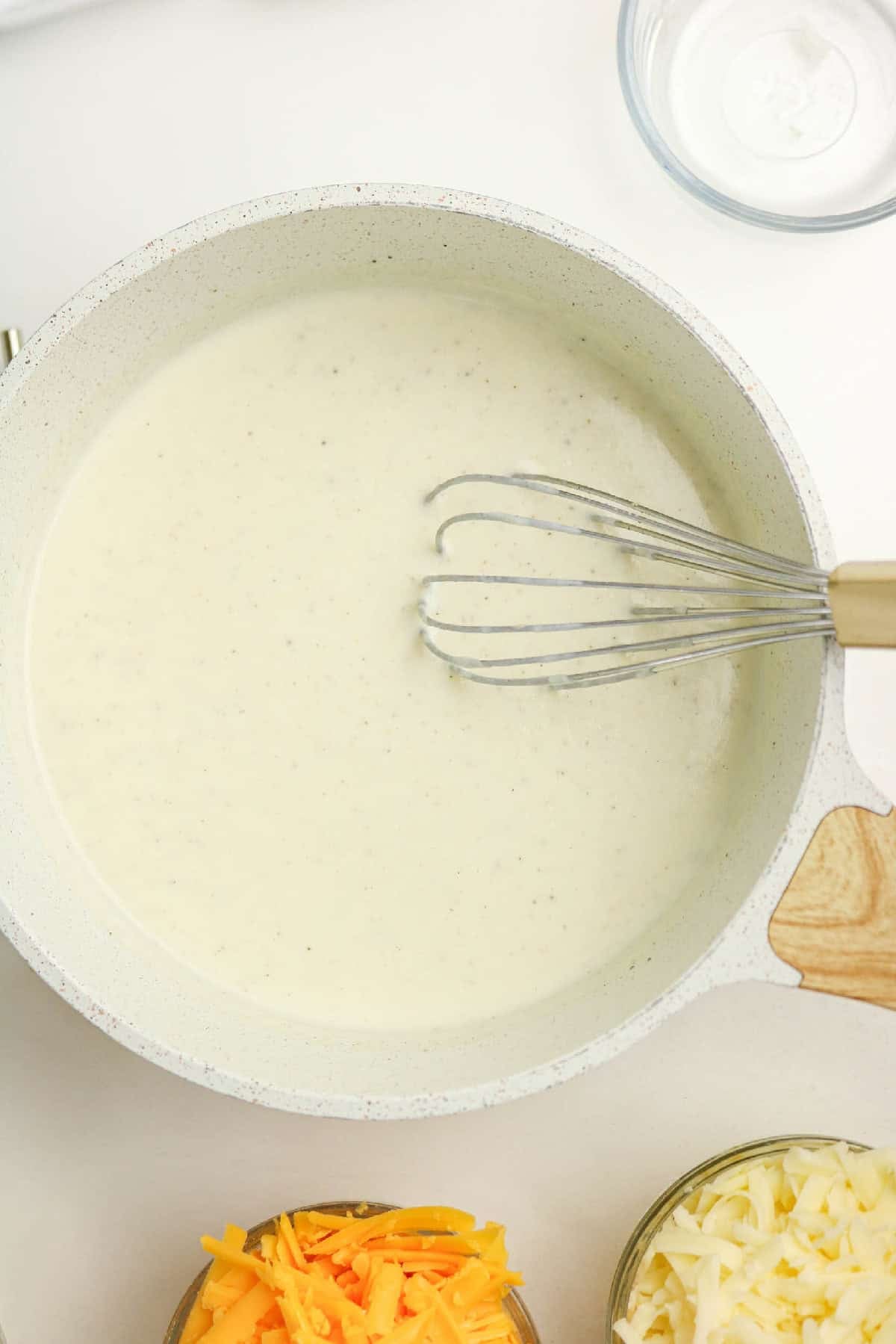 Milk whisked into the roux to create a smooth, creamy white sauce.