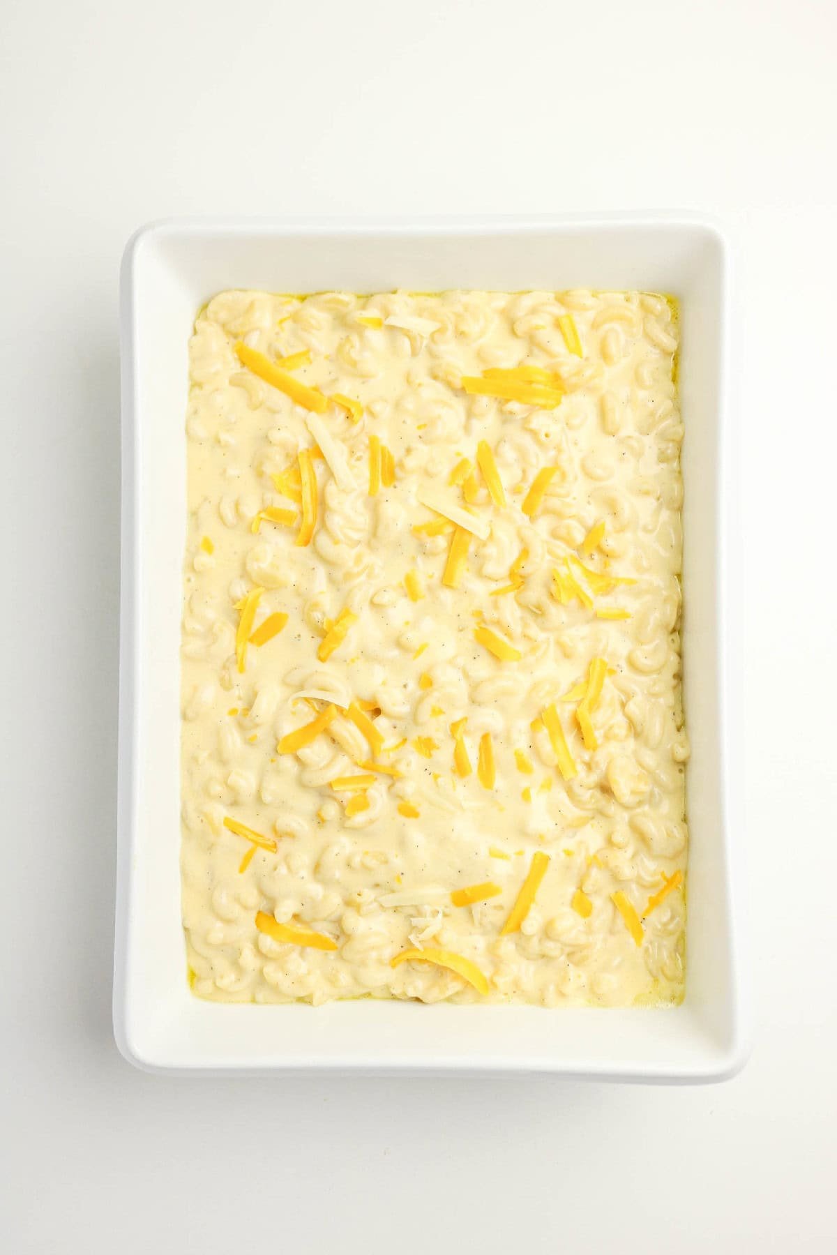 Creamy three-cheese macaroni and cheese spread into a baking dish before baking.
