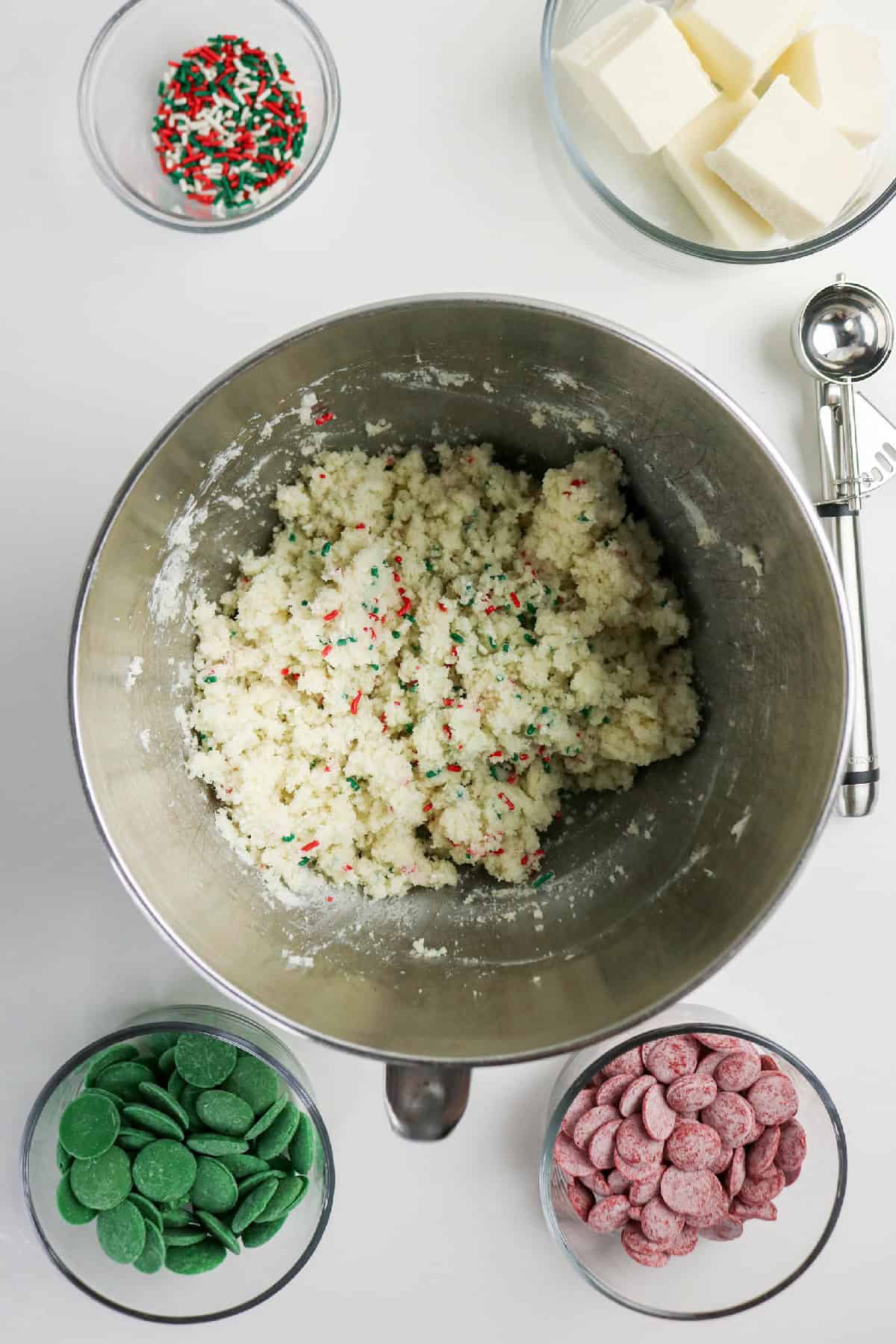 Cake pop mixture fully combined in a metal bowl with red and green sprinkles mixed throughout.