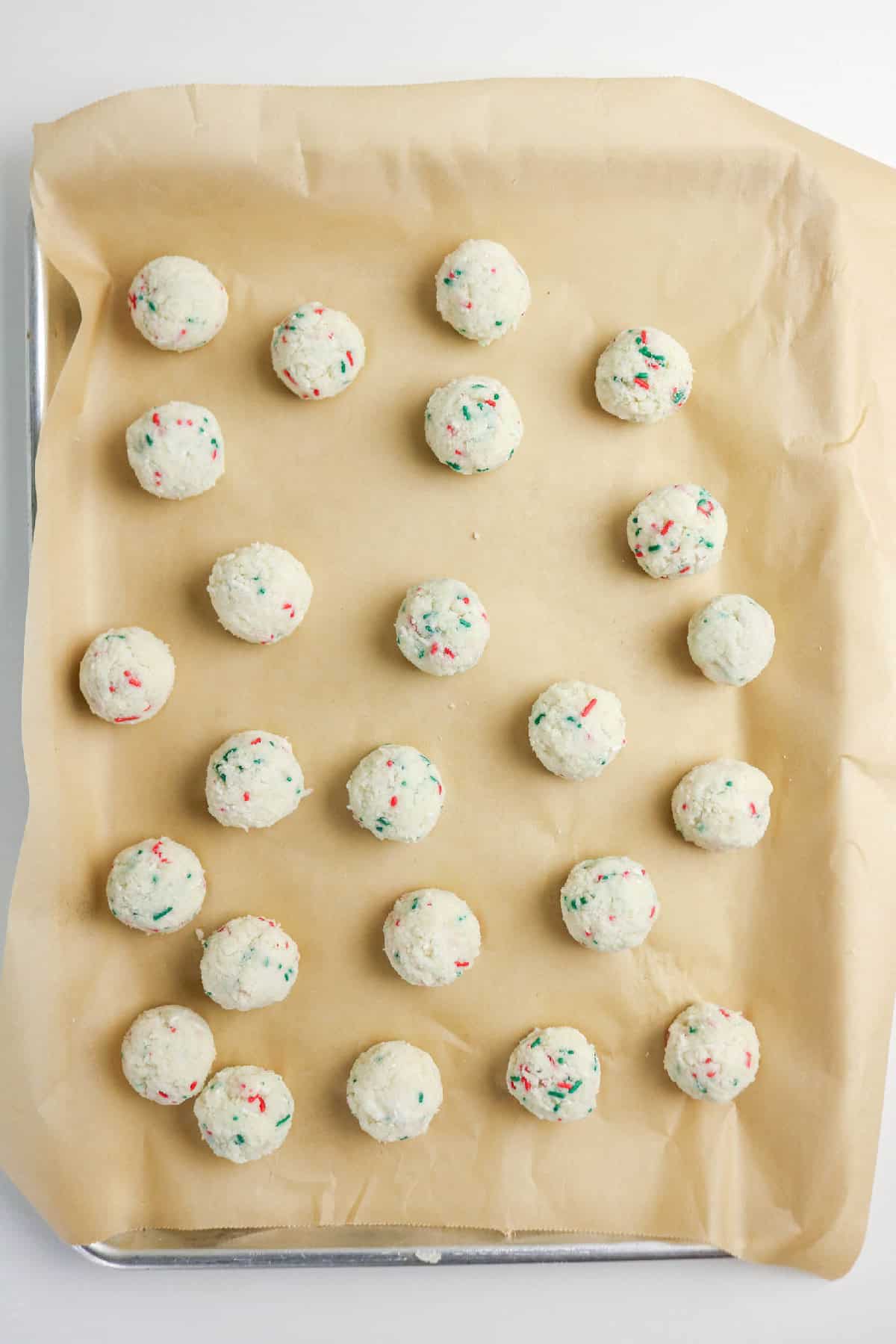 Rolled cake pop balls arranged on parchment-lined baking sheet.