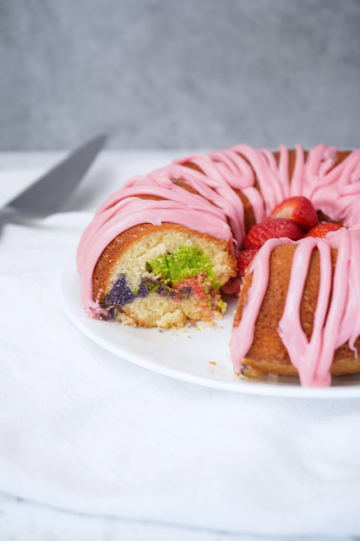 Close-up of Easter bundt cake slice showing colorful marbled interior and pink icing.