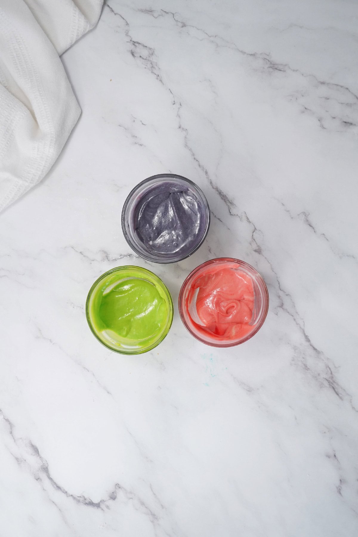 Bundt cake batter divided and colored with green, pink, and purple food coloring.