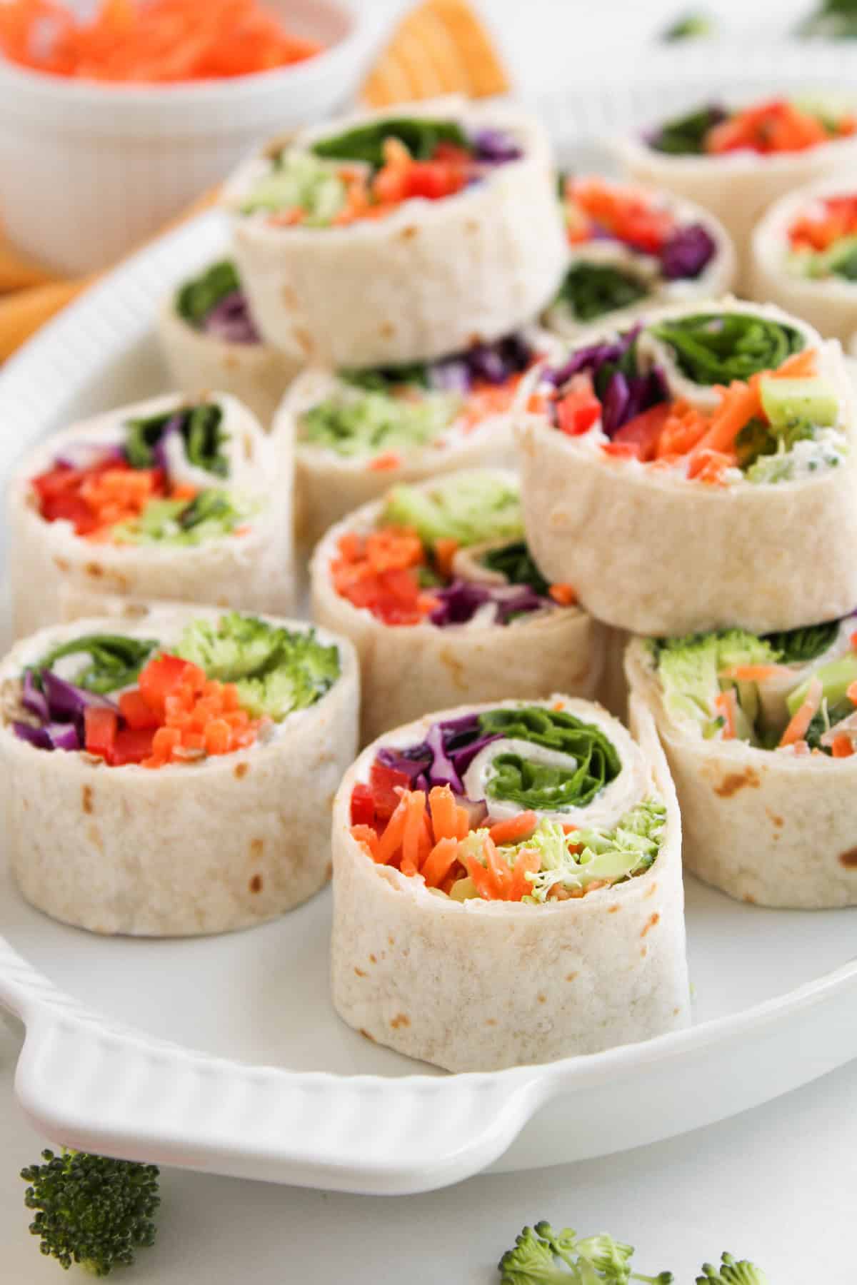 Stacked veggie pinwheels showing broccoli, red peppers, and cabbage filling.