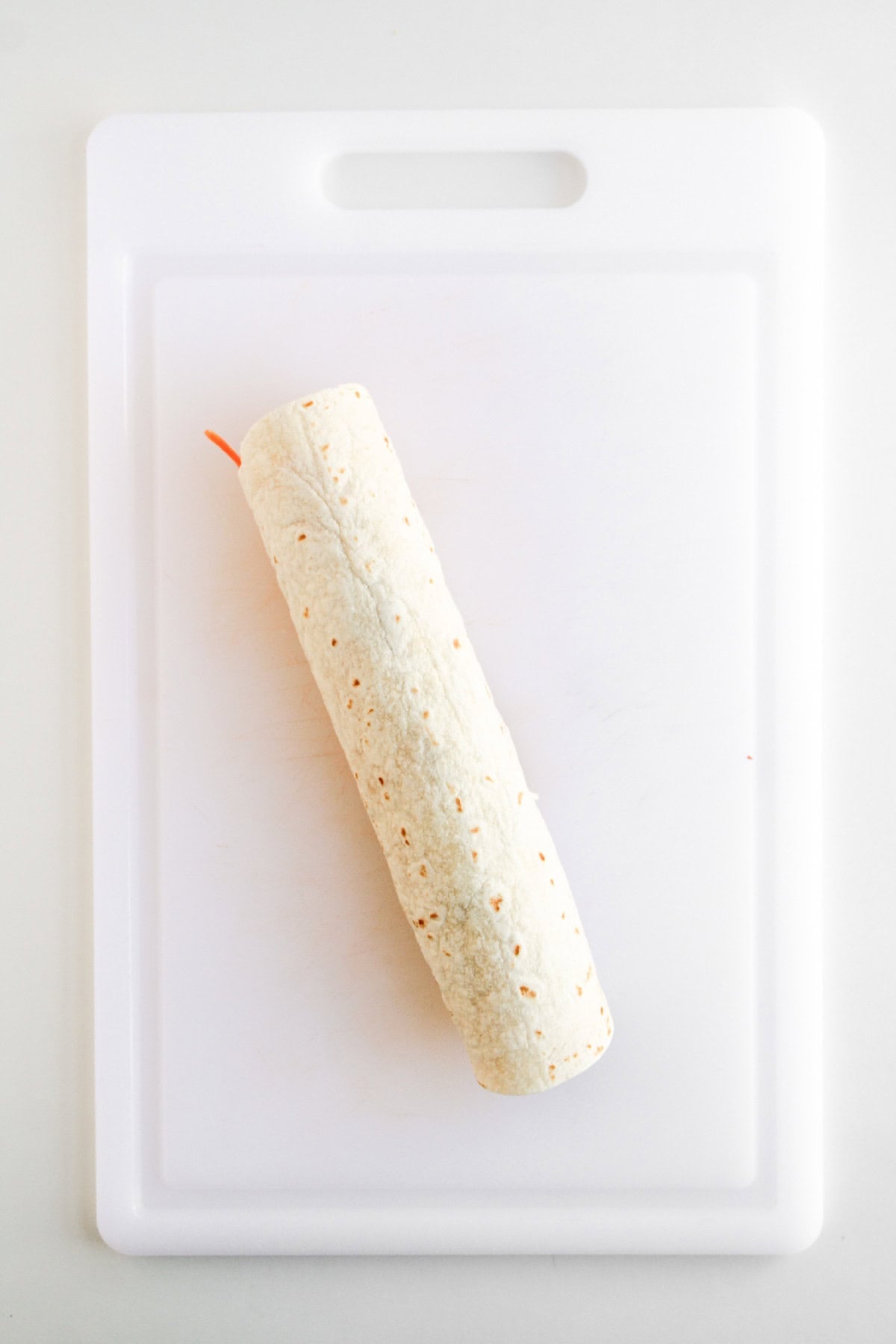 Vegetable-filled tortilla rolled tightly into a wrap for pinwheels.