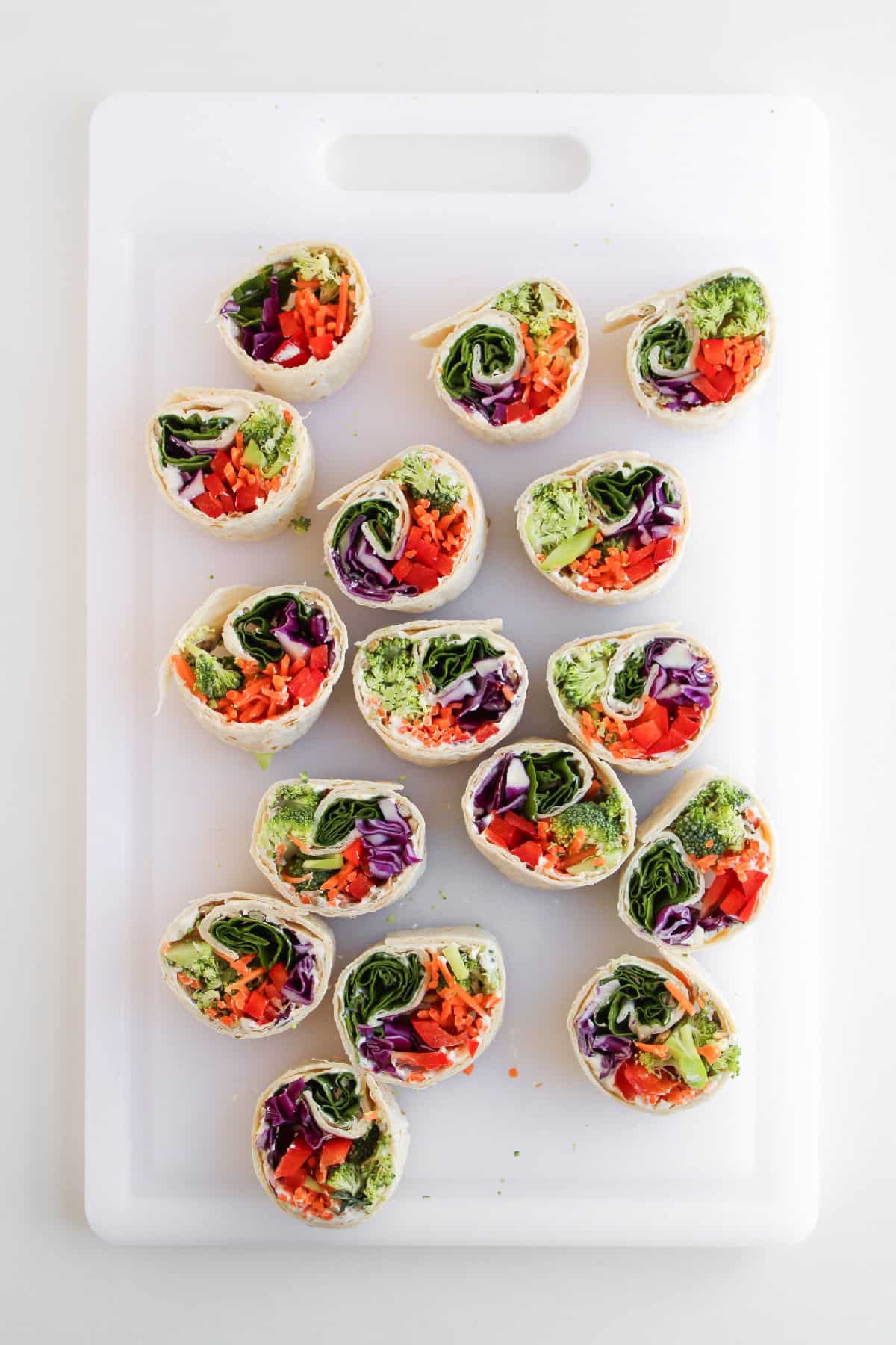 Sliced veggie pinwheel wraps arranged on a cutting board.