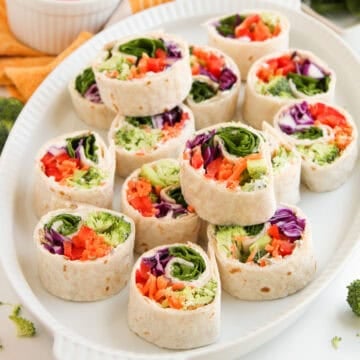 Colorful veggie tortilla roll-ups with broccoli, shredded carrots, red peppers, and purple cabbage.
