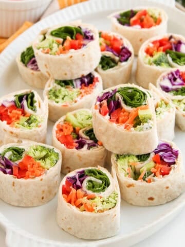 Colorful veggie tortilla roll-ups with broccoli, shredded carrots, red peppers, and purple cabbage.