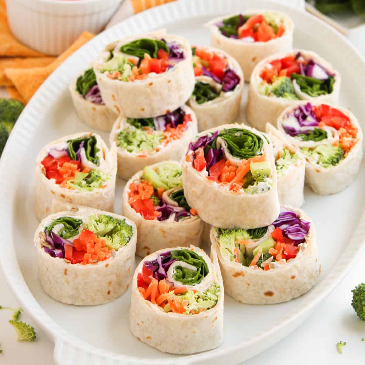 Colorful veggie tortilla roll-ups with broccoli, shredded carrots, red peppers, and purple cabbage.