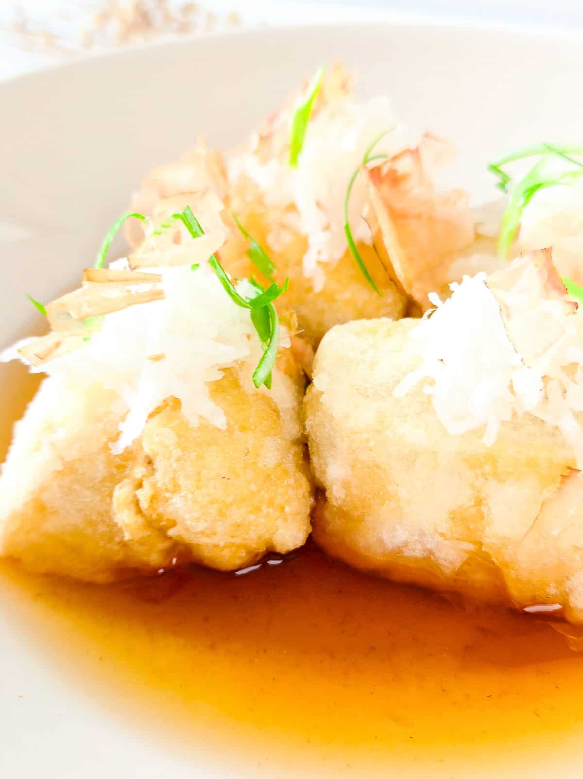 Close-up of crispy agedashi tofu showing the golden exterior and light dashi sauce.