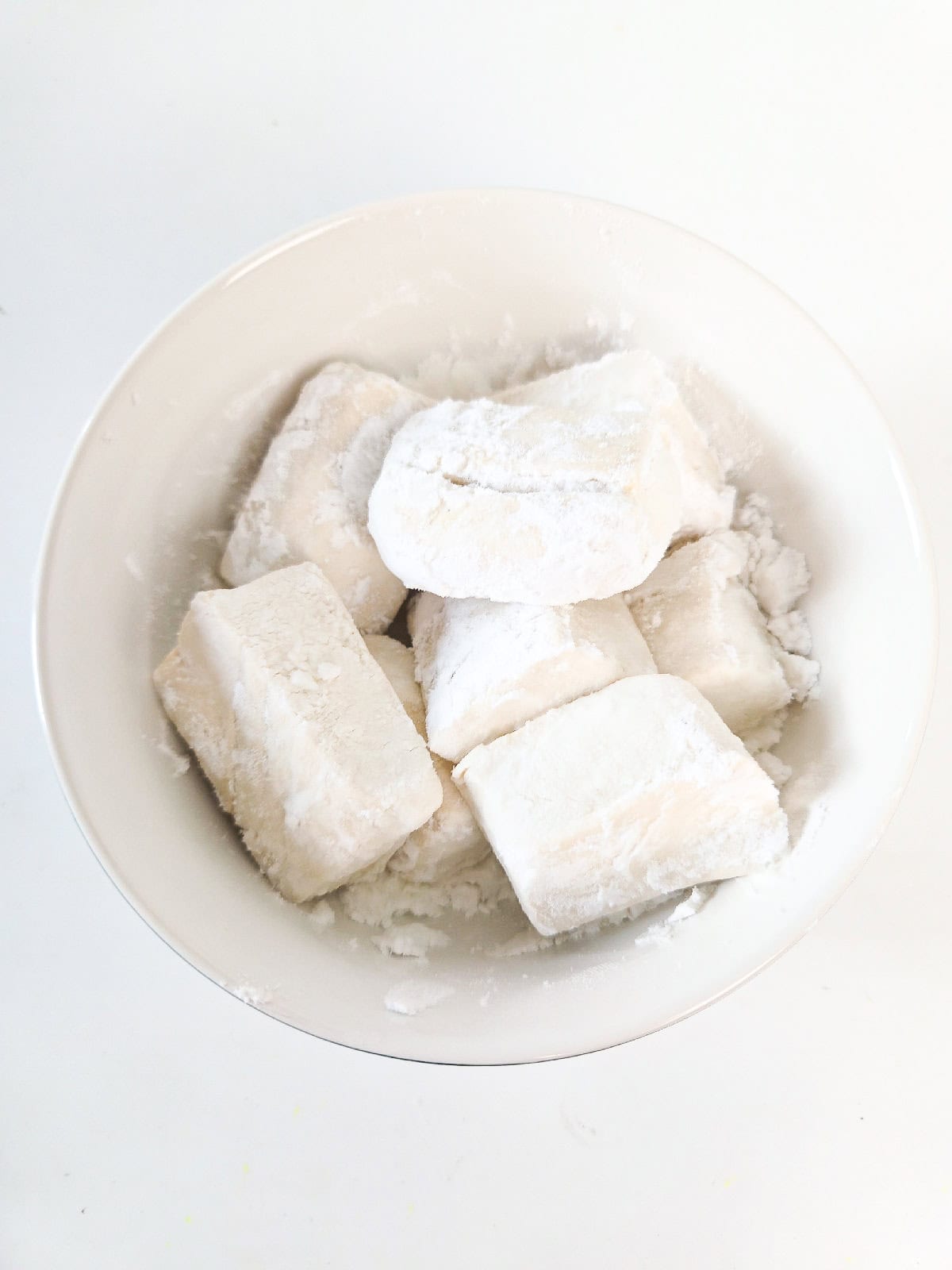 Coating tofu pieces with potato starch before frying.