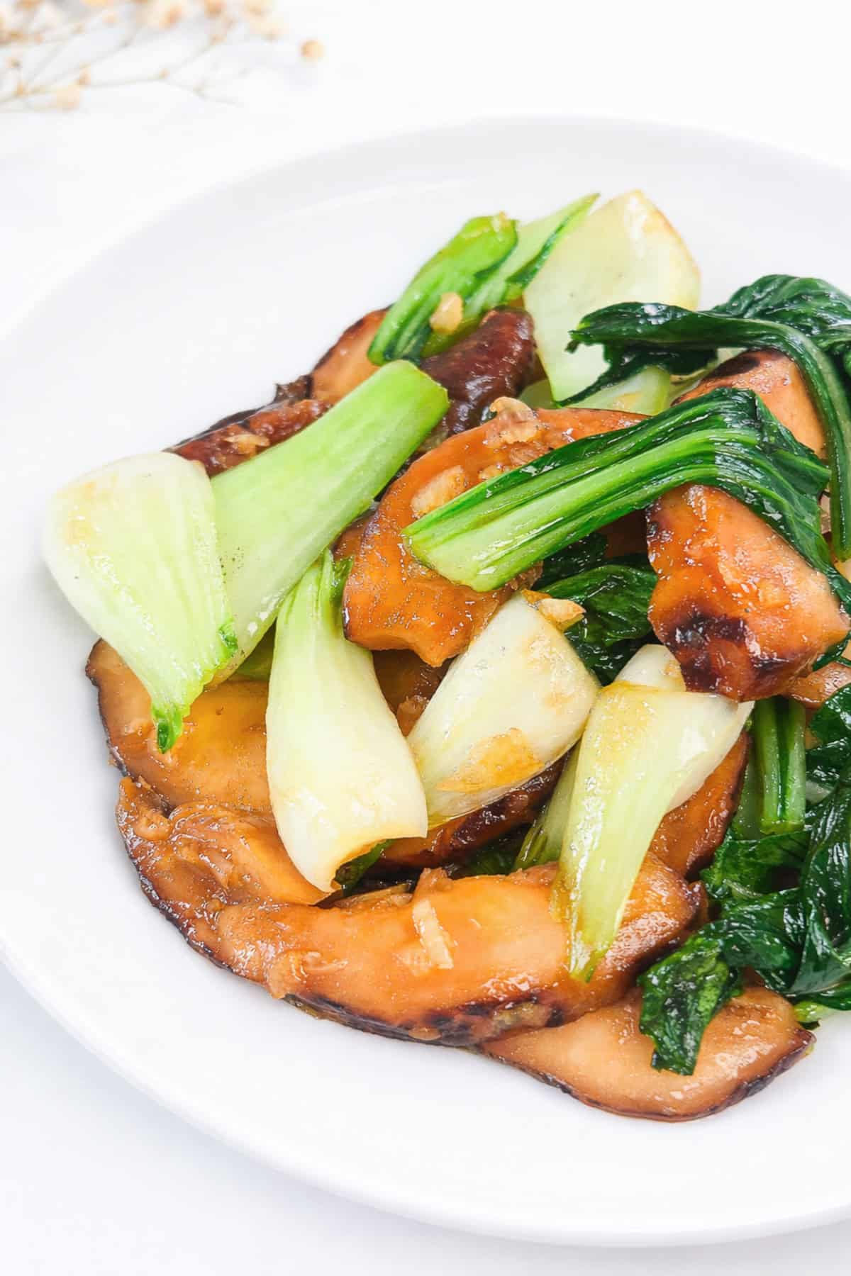 Close-up of bok choy and shiitake mushroom stir fry with glossy garlic sauce.