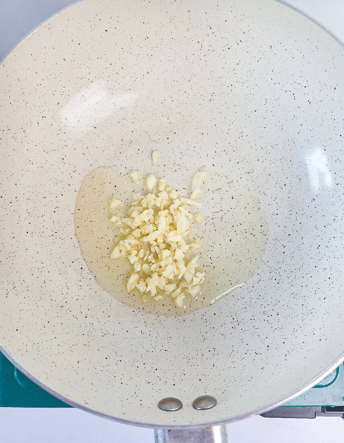Minced garlic sautéing in oil in a large pan.