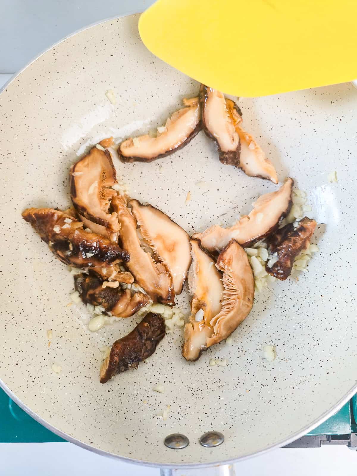 Stir-frying shiitake mushrooms and garlic in a pan.