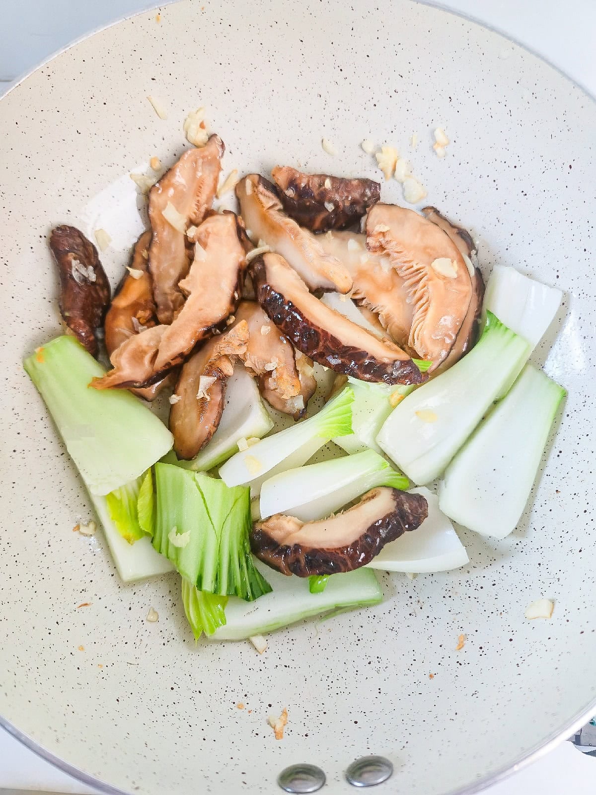 Adding bok choy to mushrooms during stir-fry.
