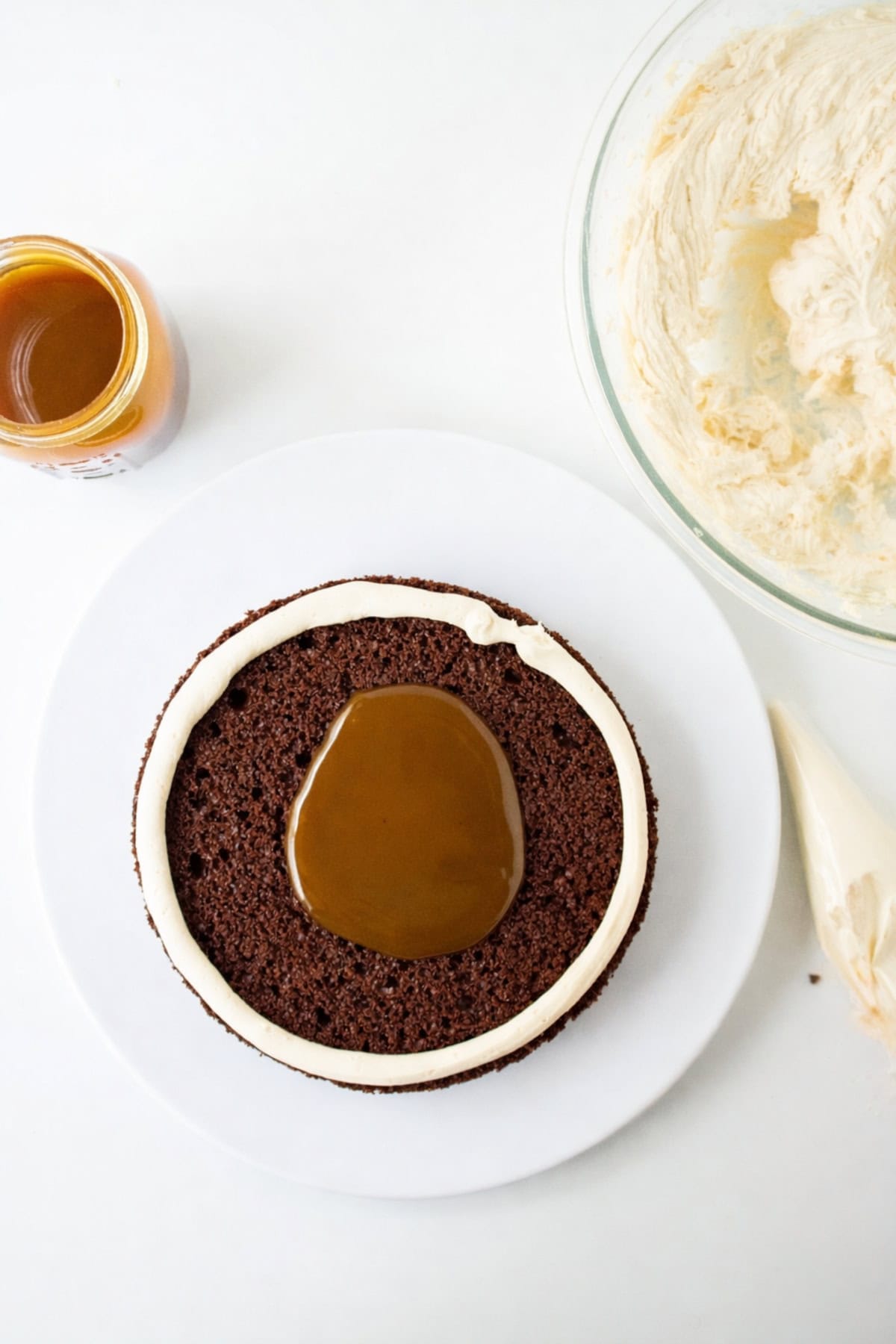 Caramel sauce spooned into the center of a buttercream ring on a chocolate cake layer.