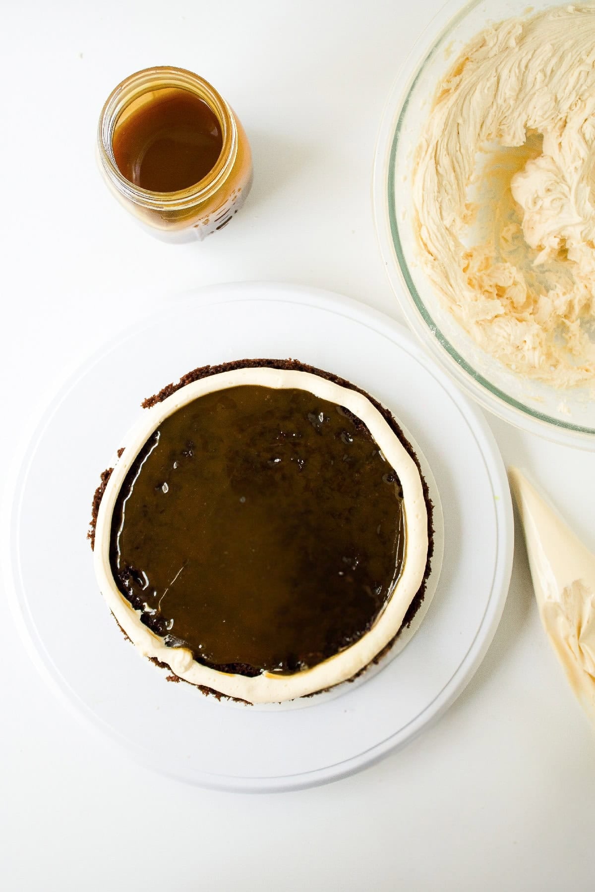 Caramel filling spread evenly inside a buttercream border on a chocolate cake layer.
