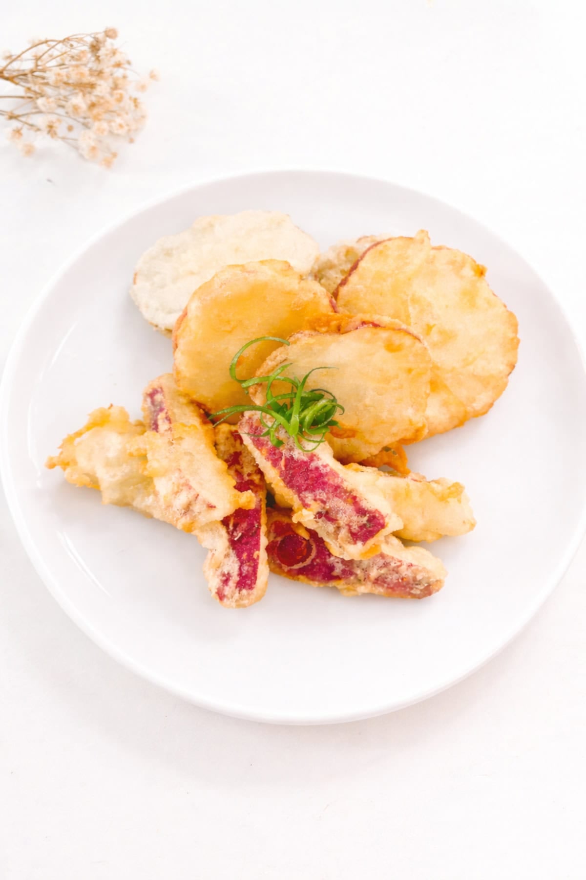Crispy sweet potato tempura served on a white plate with a light golden batter.