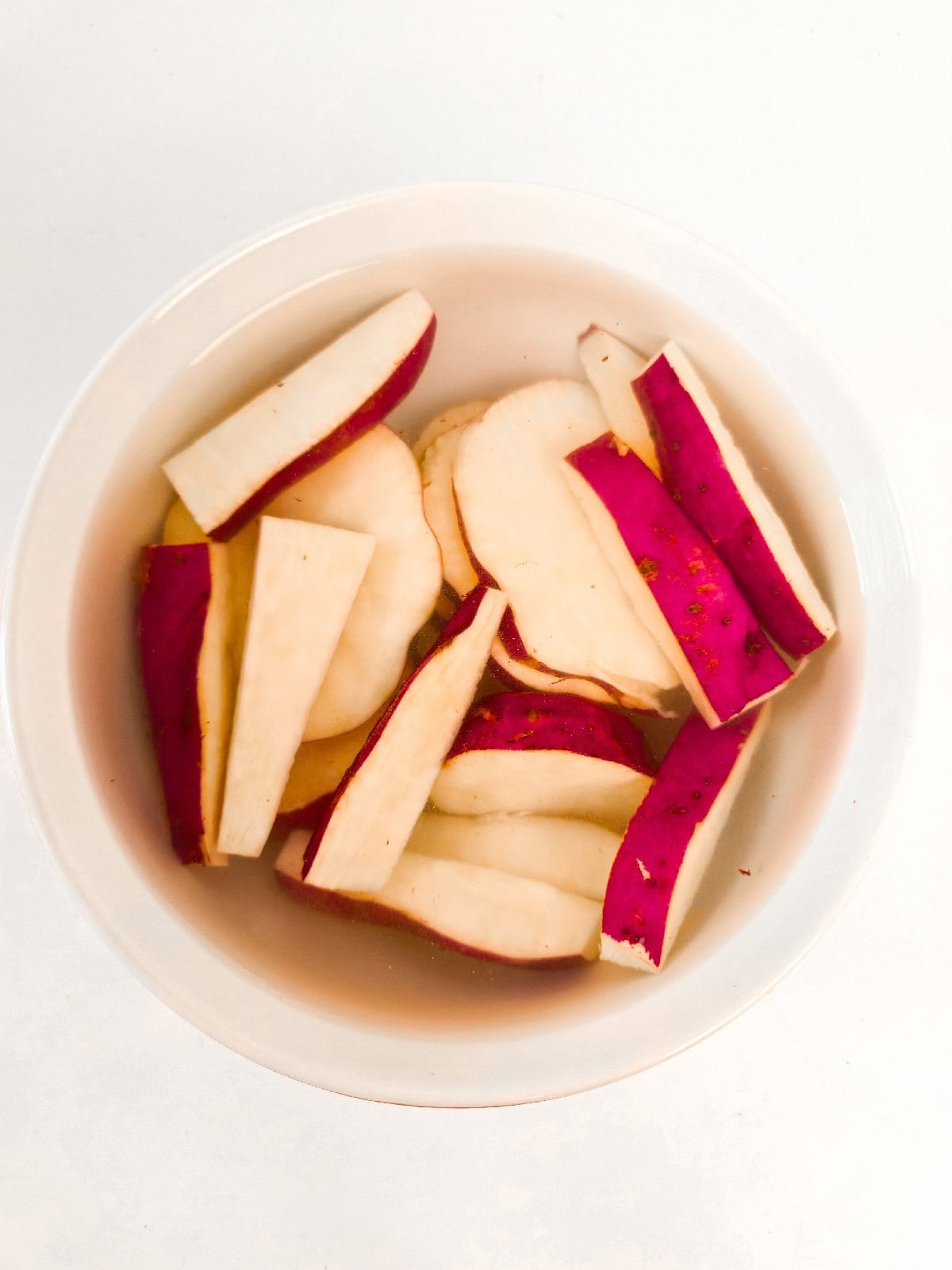 Sliced sweet potatoes soaking in water to prevent browning.