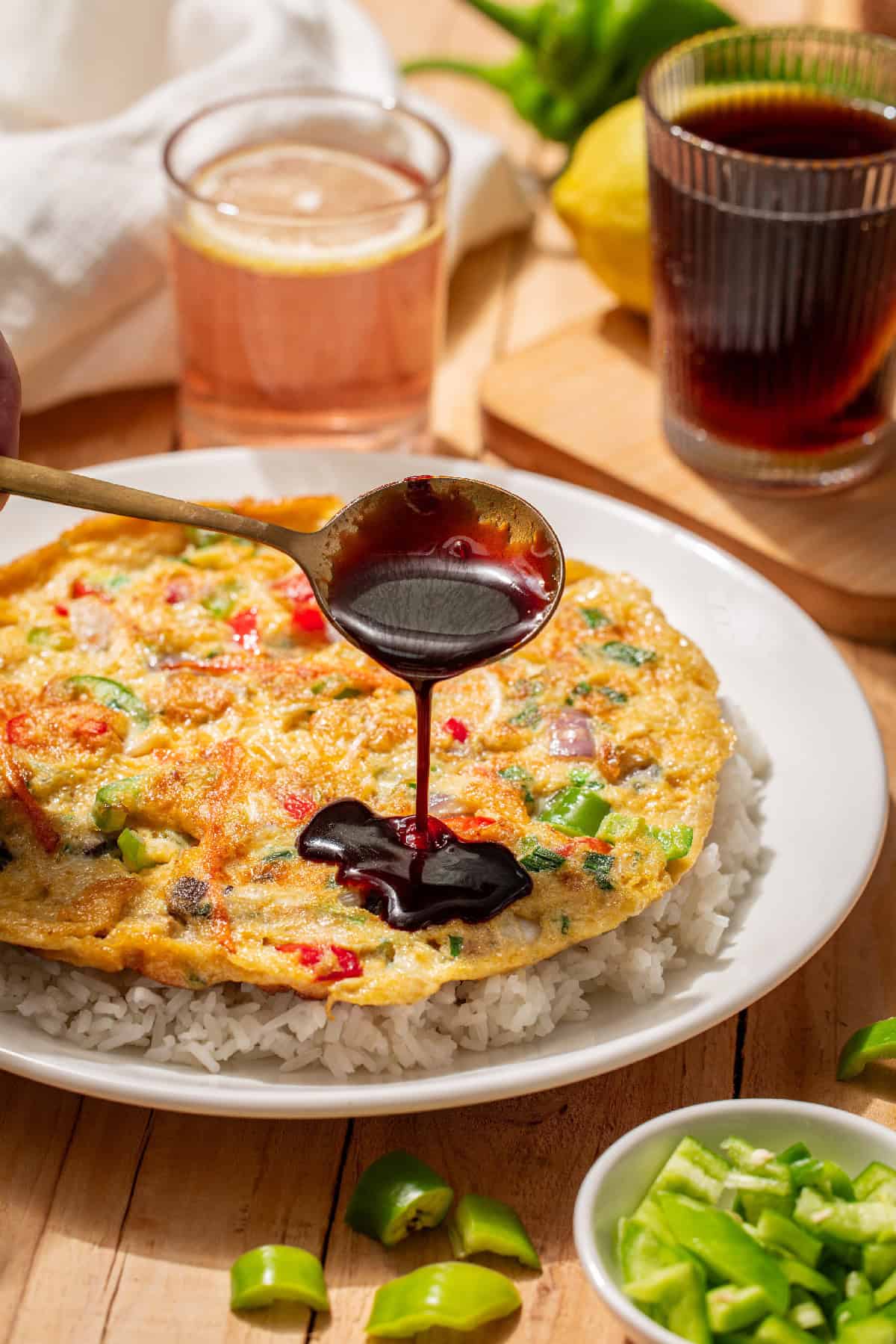 Golden vegetable egg foo young drizzled with rich brown sauce and topped with green onions over white rice.