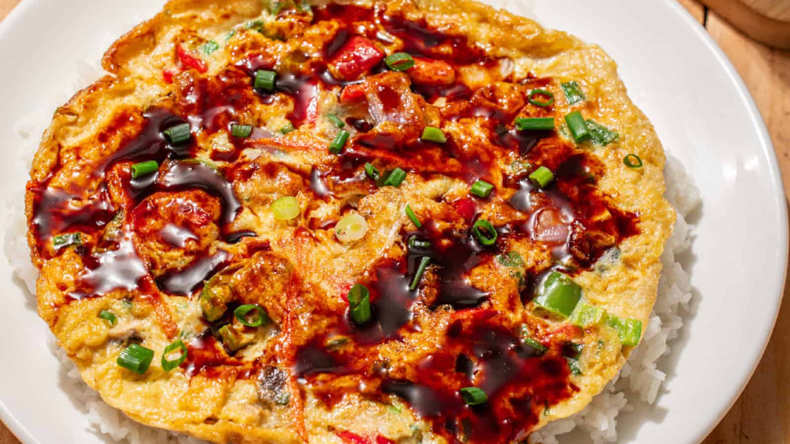 Vegetable egg foo young topped with savory brown sauce and green onions over steamed rice.