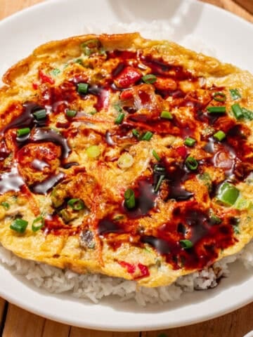Vegetable egg foo young with scallions and brown sauce served over white rice.