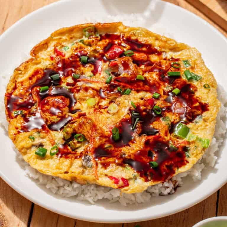 Vegetable egg foo young with scallions and brown sauce served over white rice.