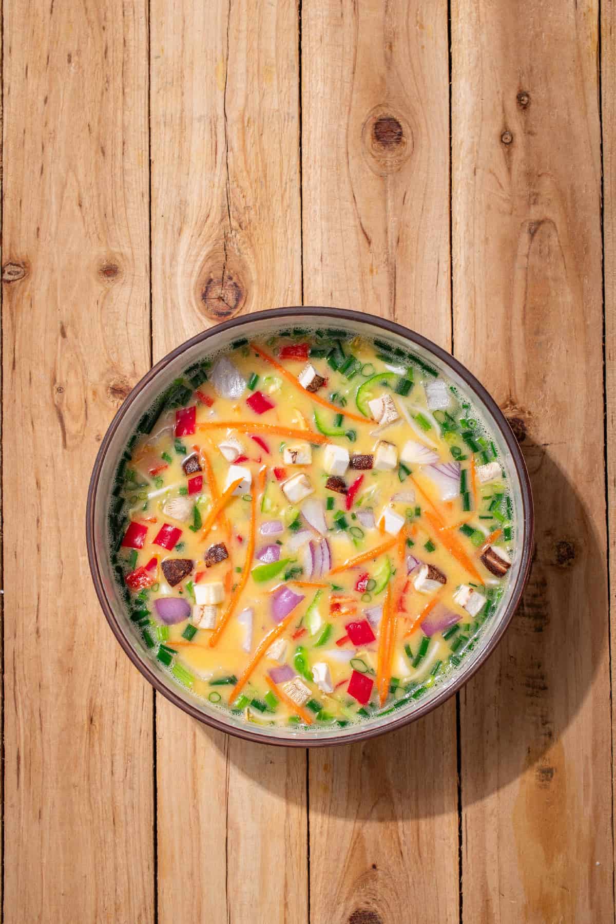 Vegetable egg foo young mixture with onions, bell peppers, mushrooms, and carrots ready for frying.